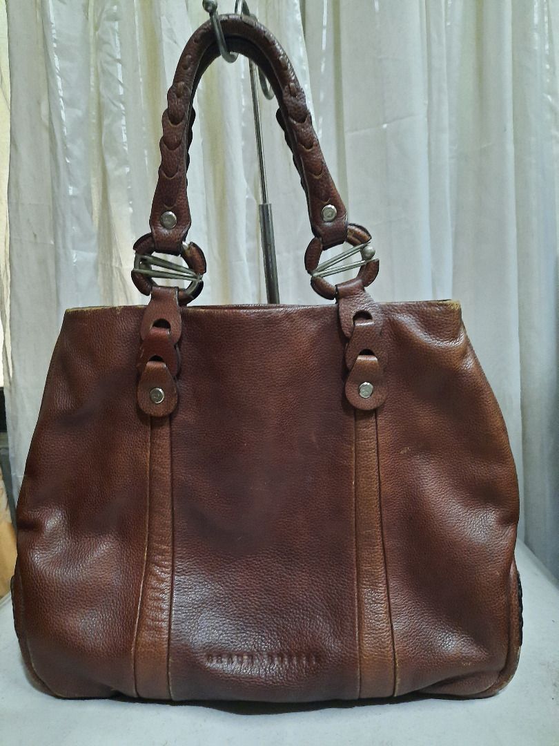 Braun Buffel brown leather tote bag (Category: Luxury Bags & Wallets) located in Quezon City. Submitted by dcmcentral (Listing ID 1470594506, Image 1). Description: - Brand: Braun Buffel - Color: Classic Brown - Material: Premium textured leather with structured depth - Handles: Stylish braided double handles with metal ring accents - Design: Vertical stitched panels and debossed brand logo - Functionality: Spacious interior with a reinforced bot