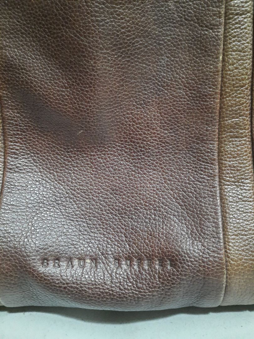 Braun Buffel brown leather tote bag (Category: Luxury Bags & Wallets) located in Quezon City. Submitted by dcmcentral (Listing ID 1470594506, Image 2). Description: - Brand: Braun Buffel - Color: Classic Brown - Material: Premium textured leather with structured depth - Handles: Stylish braided double handles with metal ring accents - Design: Vertical stitched panels and debossed brand logo - Functionality: Spacious interior with a reinforced bot