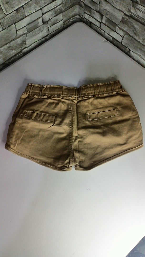 Brown casual shorts with drawstring and patch detail (Category: Shorts) located in Antipolo. Submitted by reahespiritu (Listing ID 1470619338, Image 2). Description: - Color: Brown - Material: Soft, comfortable fabric ideal for daily wear - Waistband: Elastic with an adjustable white drawstring - Design details: Small orange patch on the left leg and two back pockets with flap closures - Cut: Short length with a stylish curved hem.