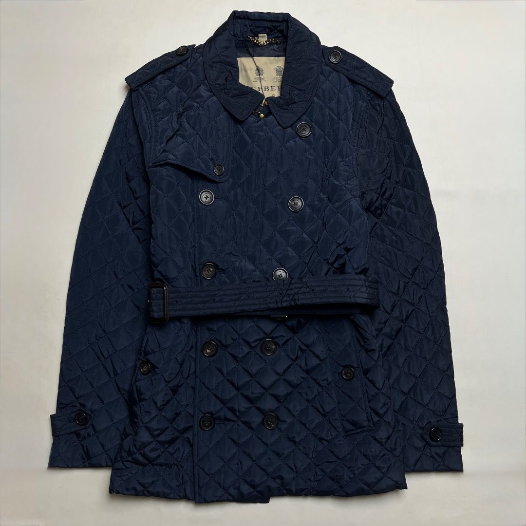 Burberry Quilted Nylon Trench Coat (Category: Coats, Jackets and Outerwear) located in Caloocan City. Submitted by achilles_grails (Listing ID 1470592994, Image 1). Description: - Brand: Burberry - Style: Quilted Nylon Trench Coat / Double-Breasted Jacket - Color: Dark Navy Blue - Size: XL (185/104B) - Material: 100% Polyester outer shell, 100% Viscose lining - Features: Diamond-quilted pattern, matching waist belt, shoulder epaulettes, branded b