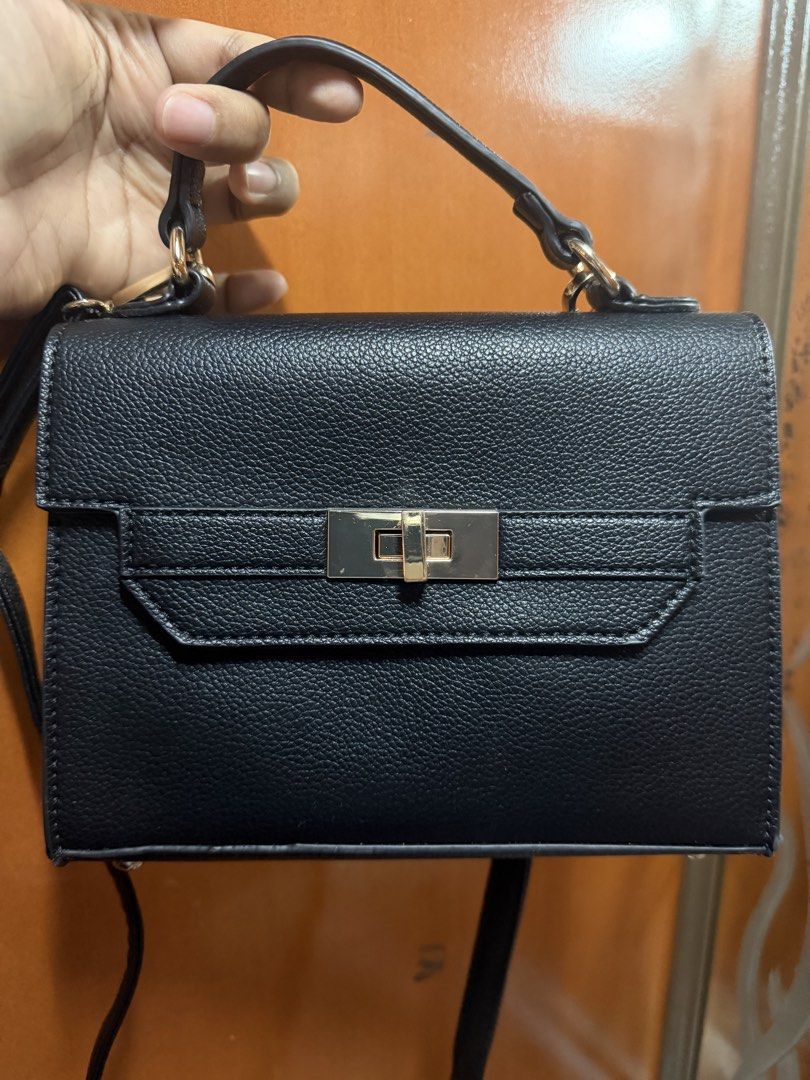 Call it Spring Black Sling Bag (Category: Luxury Bags & Wallets) located in Pasig City. Submitted by aprilluxcloset0812 (Listing ID 1470608696, Image 2). Description: - Structured black handbag with a stylish pebbled texture, with minor scratches in hardware - Elegant gold metal hardware and twist-lock flap closure - Features a convenient top handle and adjustable shoulder strap - Chic diamond-shaped logo plaque on the back - Excellent, clean con