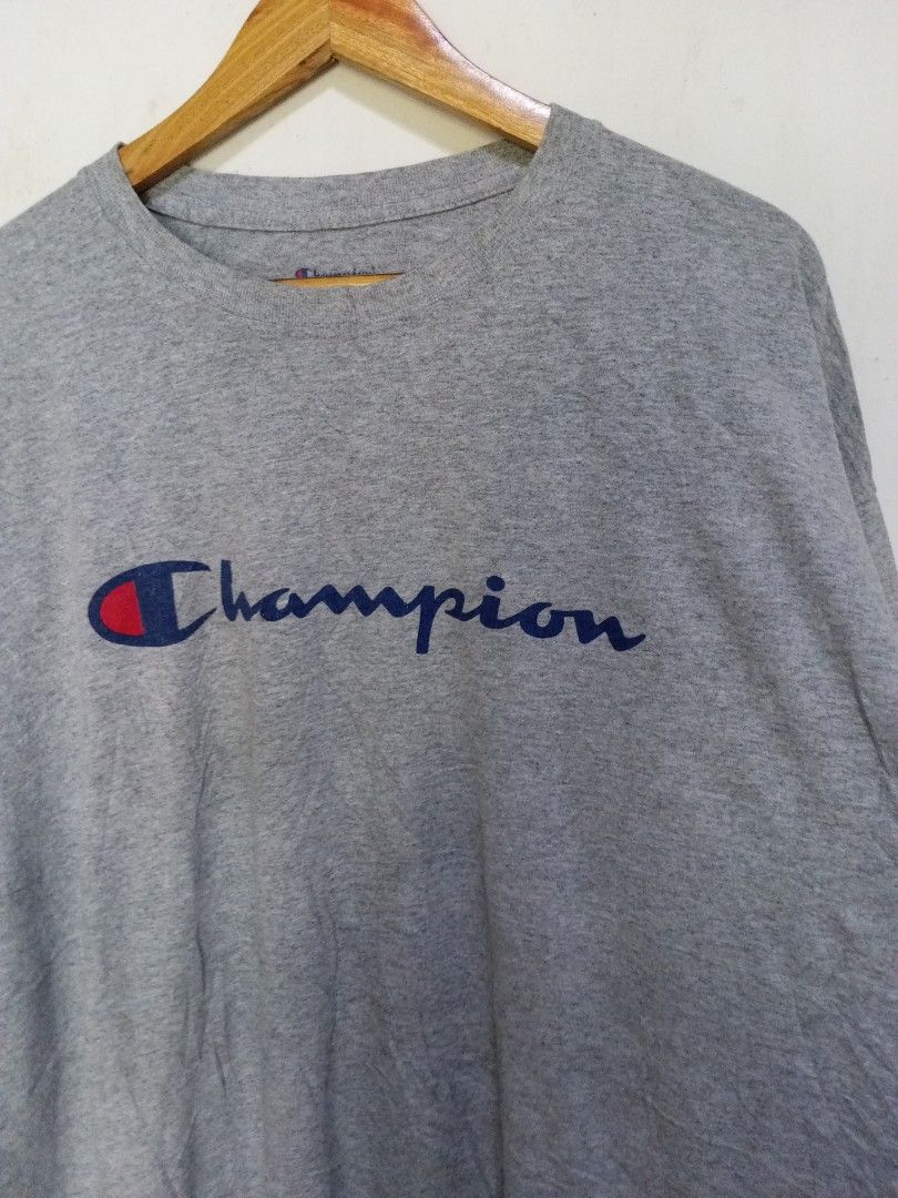 Champion Script Logo Grey T-Shirt 2XL (Category: Tshirts & Polo Shirts ) located in Magdalena. Submitted by magdalenathrift20 (Listing ID 1470671910, Image 3). Description: - Brand: Champion - Color: Grey - Size: 2XL (Width: 27", Length: 31") - Material: 100% cotton, made in Honduras - Condition/Details: Authentic athleticwear with classic crewneck and printed chest script logo.