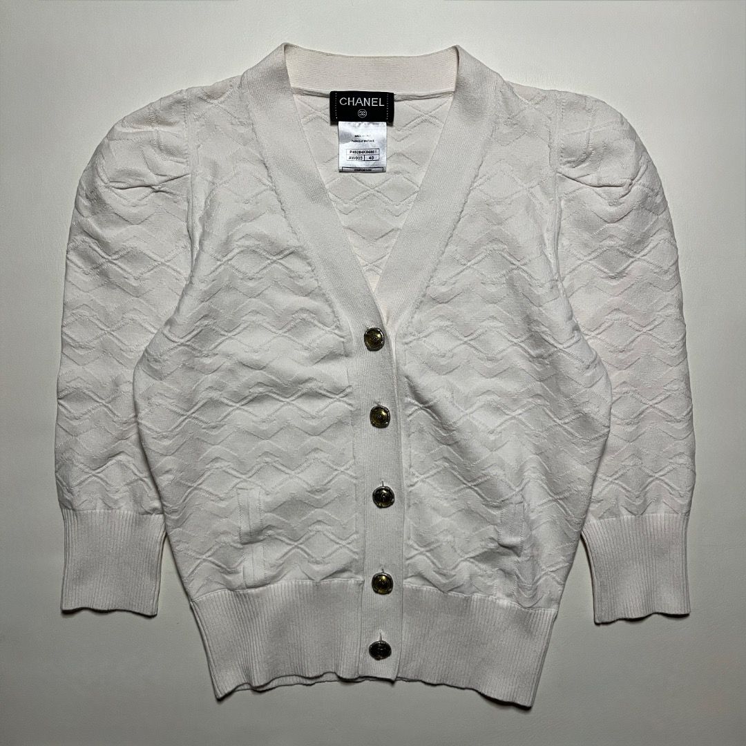 Chanel White Knitted Cardigan Size 40 (Category: Coats, Jackets and Outerwear) located in Caloocan City. Submitted by achilles_grails (Listing ID 1470594260, Image 2). Description: - Brand: Chanel - Item: White knit cardigan - Size: 40 (Made in Italy) - Material: Cotton, nylon, and polyurethane blend - Design: V-neck, button-front with gold-tone CC logo buttons - Details: Textured diamond pattern, short sleeves, and ribbed trim - Condition: Excel
