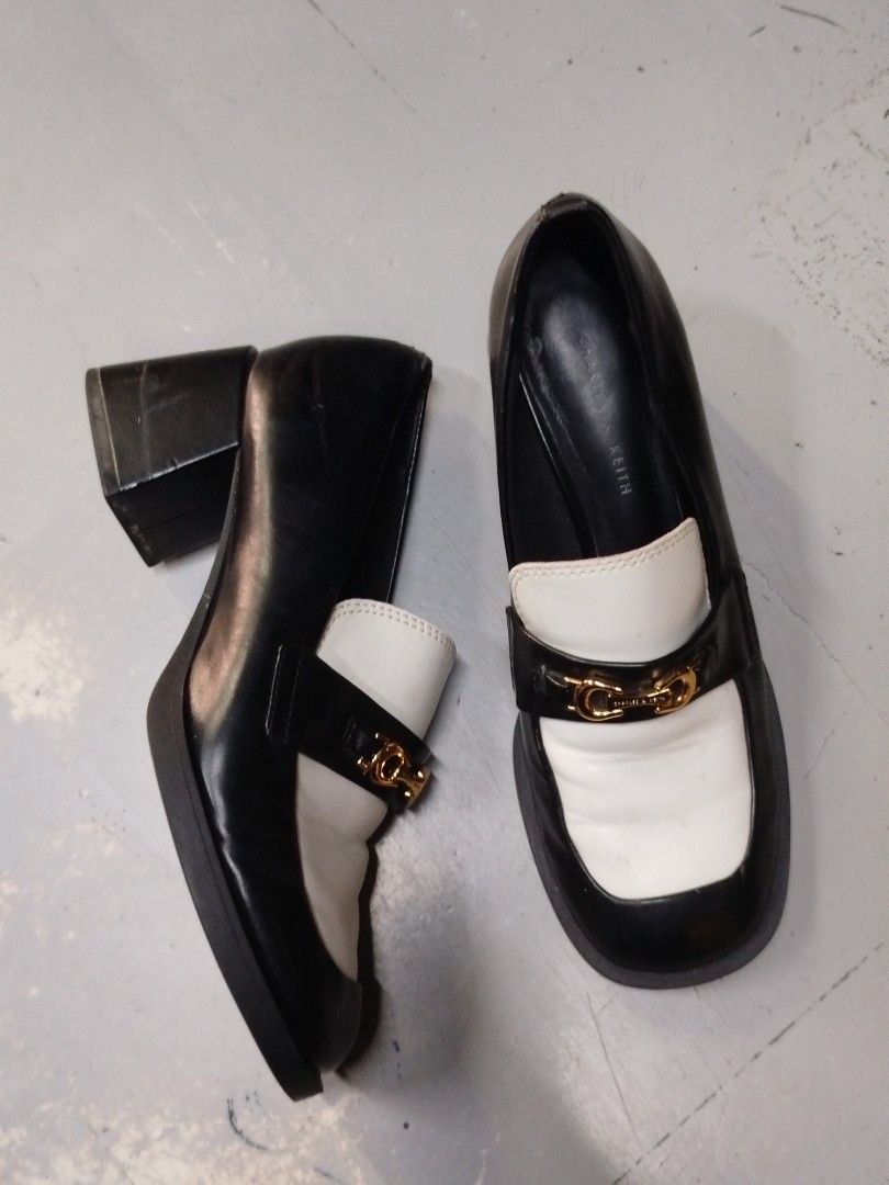 Charles & Keith Two-Tone Chunky Heel Loafers (Category: Loafers) located in Quezon City. Submitted by epoquebyjaz (Listing ID 1470640702, Image 3). Description: - Brand/Model: Charles & Keith Two-Tone Loafers - Color: Black and White - Design: Slip-on with square toes and gold-tone horsebit hardware - Heels: Chunky block heels - Condition: Soles and heels are intact; shows minor natural creasing on the white leather upper from normal wear.