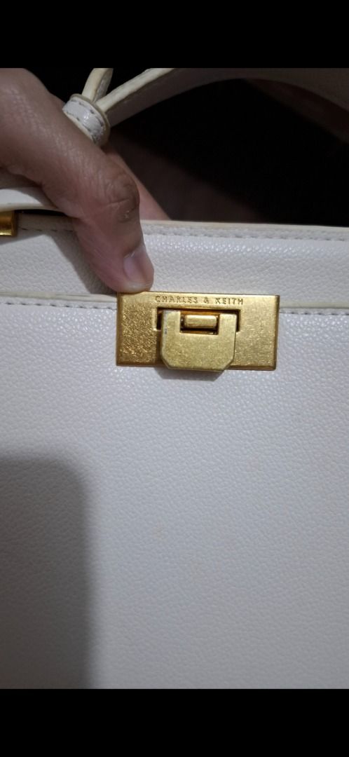 Charles & Keith White Structured Crossbody Bag (Category: Cross-body Bags) located in Cavite. Submitted by chinkee0215020 (Listing ID 1470737996, Image 2). Description: Selling an authentic Charles & Keith white structured bag featuring elegant gold hardware. It comes with a top handle, adjustable strap, and a secure turn-lock closure. Inside, you'll find a fabric lining and a zippered pocket for your essentials, plus a cute detachable small tag 