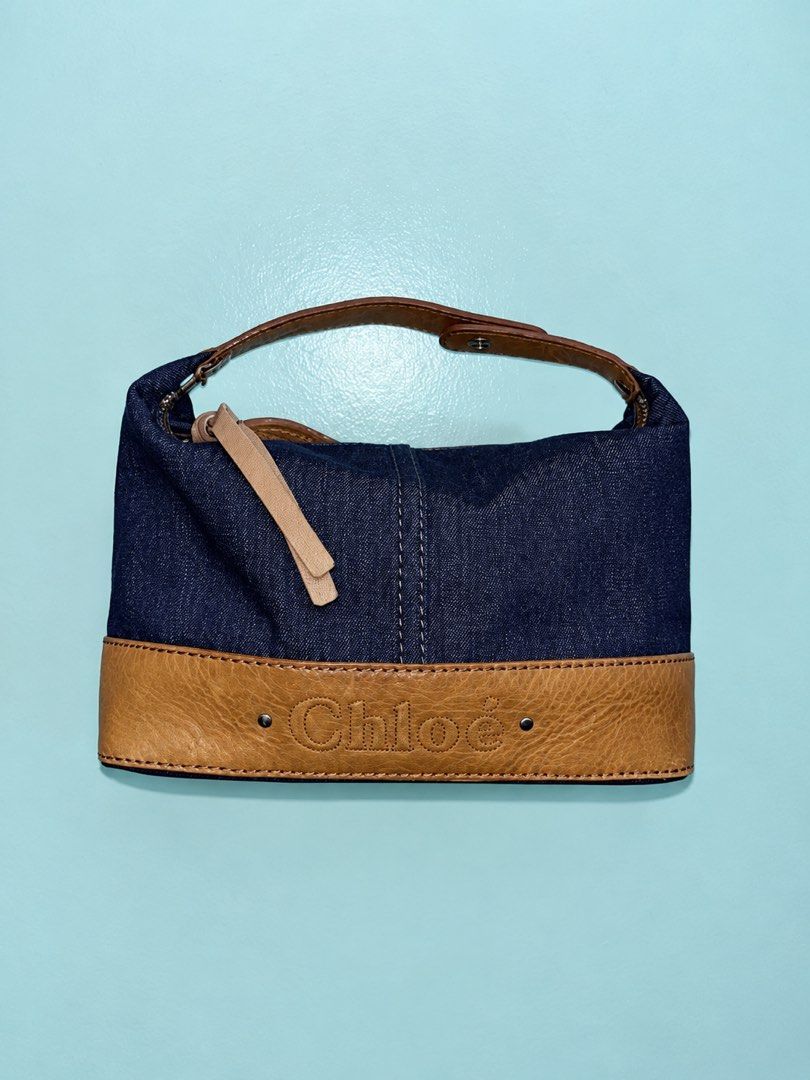 Chloé Denim and Leather Shoulder Bag (Category: Luxury Bags & Wallets) located in Bustos. Submitted by theprelovedshopbulacan (Listing ID 1470704391, Image 1). Description: - Authentic Chloé shoulder bag - Dark blue denim with brown leather trim - Debossed Chloé logo on bottom panel - Single brown leather strap with snap button detail - Metallic zip closure with dual leather pull tabs - Clean cream fabric lining - Vintage-finish hardware - PM for