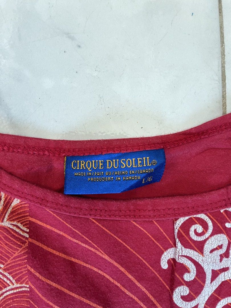 Cirque du Soleil Red Spaghetti Strap Tank Top Size L (Category: Sleeveless) located in Caloocan City. Submitted by kimronnel (Listing ID 1470578900, Image 2). Description: - Brand: Cirque du Soleil - Size: Large - Origin: Made in Canada - Design: Patchwork-style graphic print with abstract motifs, swirls, and patterns - Features: Scoop neckline, thin spaghetti straps, lightweight fabric - Color: Bright red base with contrasting white and pink pri