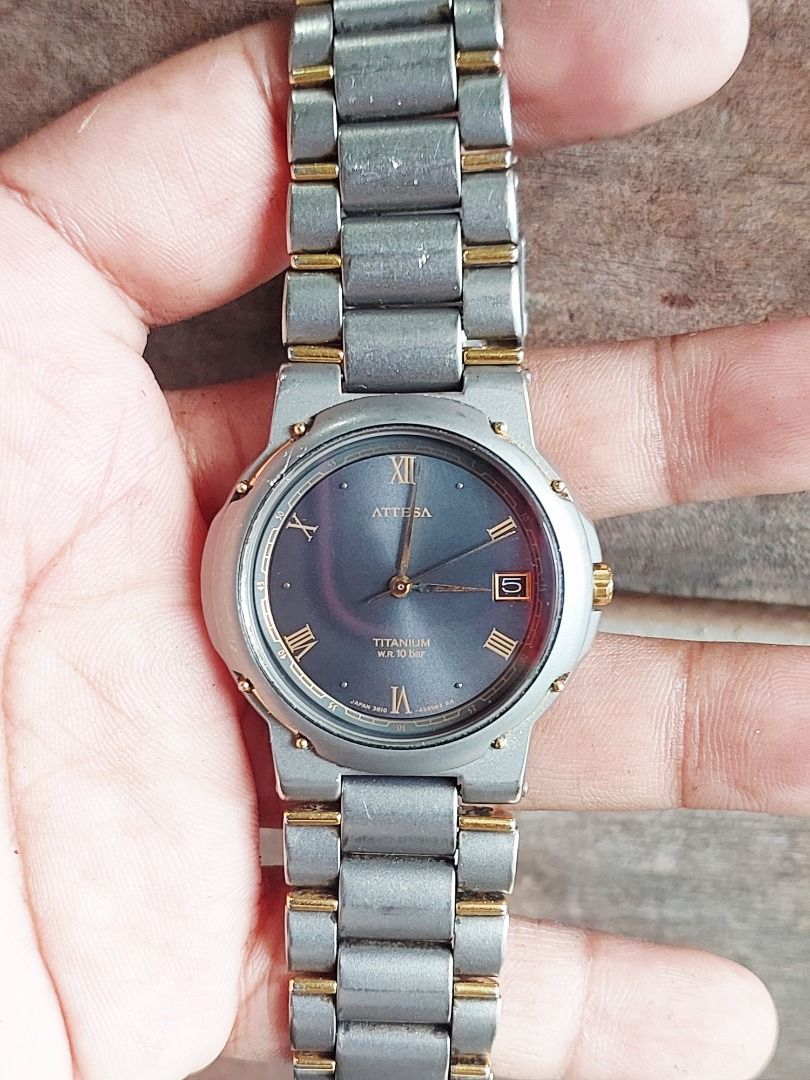 Citizen Attesa Titanium Wristwatch (Category: Men's Watches) located in Batangas. Submitted by vintageanddainty (Listing ID 1470589946, Image 2). Description: - Brand/Model: Citizen Attesa Titanium Watch - Design: Dark grey dial with Roman numerals, gold accents on bezel and bracelet, and date window at 3 o'clock - Material: Lightweight and durable titanium case and bracelet with deployment clasp - Water Resistance: 10 bar - Reference Numbers: 38