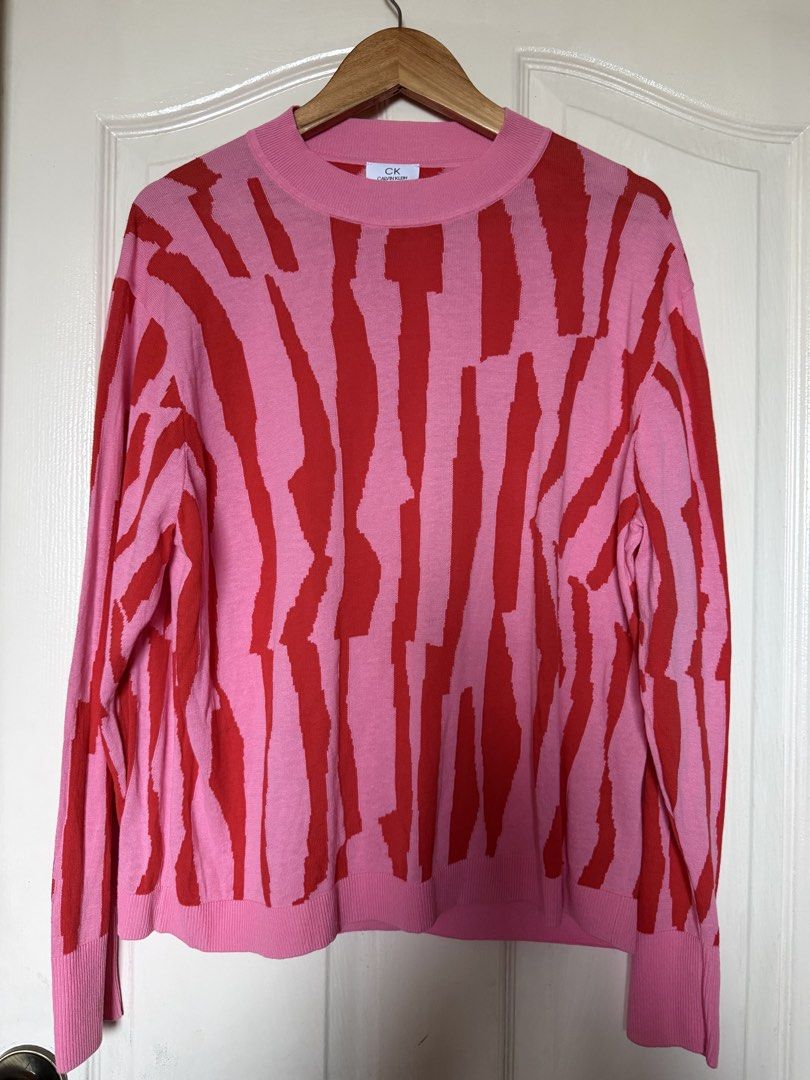 CK Calvin Klein Knit Pink and Red Abstract Pattern Sweater (Category: Longsleeves) located in La Trinidad. Submitted by rare_closet_finds (Listing ID 1470657463, Image 1). Description: - Brand: CK Calvin Klein - Color: Pink base with striking red vertical abstract print - Design: Crewneck sweater with long sleeves - Details: Ribbed cuffs and hem - Material: Soft, comfortable knit - Condition: Excellent - Perfect bright statement piece for cooler 