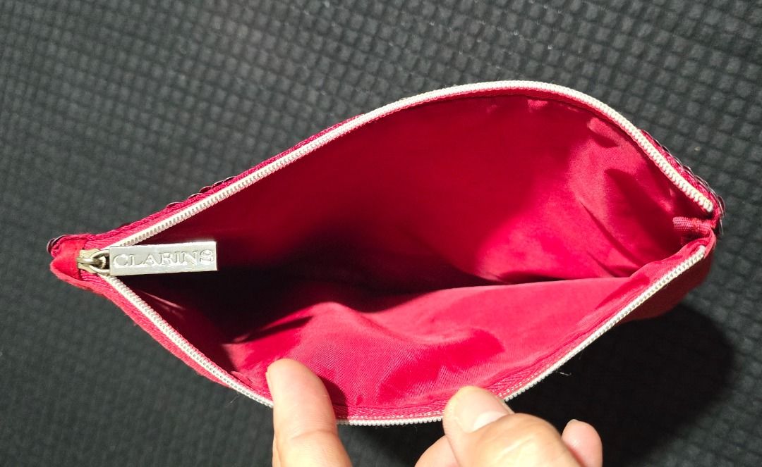 Clarins Red Cosmetic Pouch (Category: Purses & Pouches) located in Manila. Submitted by axelyuna.27 (Listing ID 1470588733, Image 2). Description: Features a zip closure with a branded silver pull tab, a solid red back, and a roomy, clean lined interior perfect for daily essentials or travel..