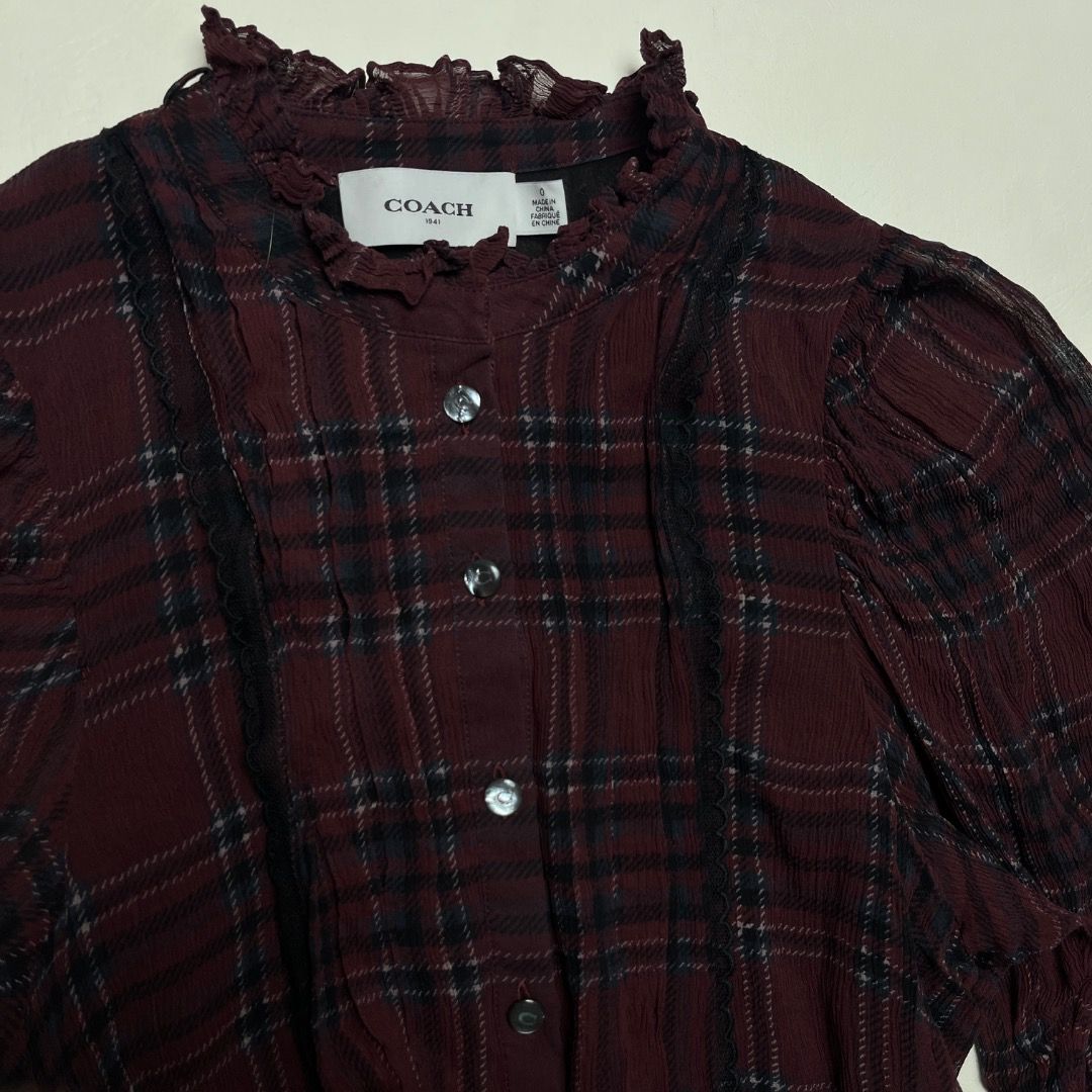 Coach 1941 Maroon Plaid Ruffle High Neck Blouse Size S (Category: Blouses) located in Caloocan City. Submitted by achilles_grails (Listing ID 1470577021, Image 2). Description: - Brand: Coach 1941 - Size: 0 - Color/Pattern: Maroon plaid - Details: High ruffled collar, button-up front with branded buttons, dark lace accents on chest - Versatility: Great for layering or wearing on its own - Condition: Clean inside and out, from a smoke-free home.