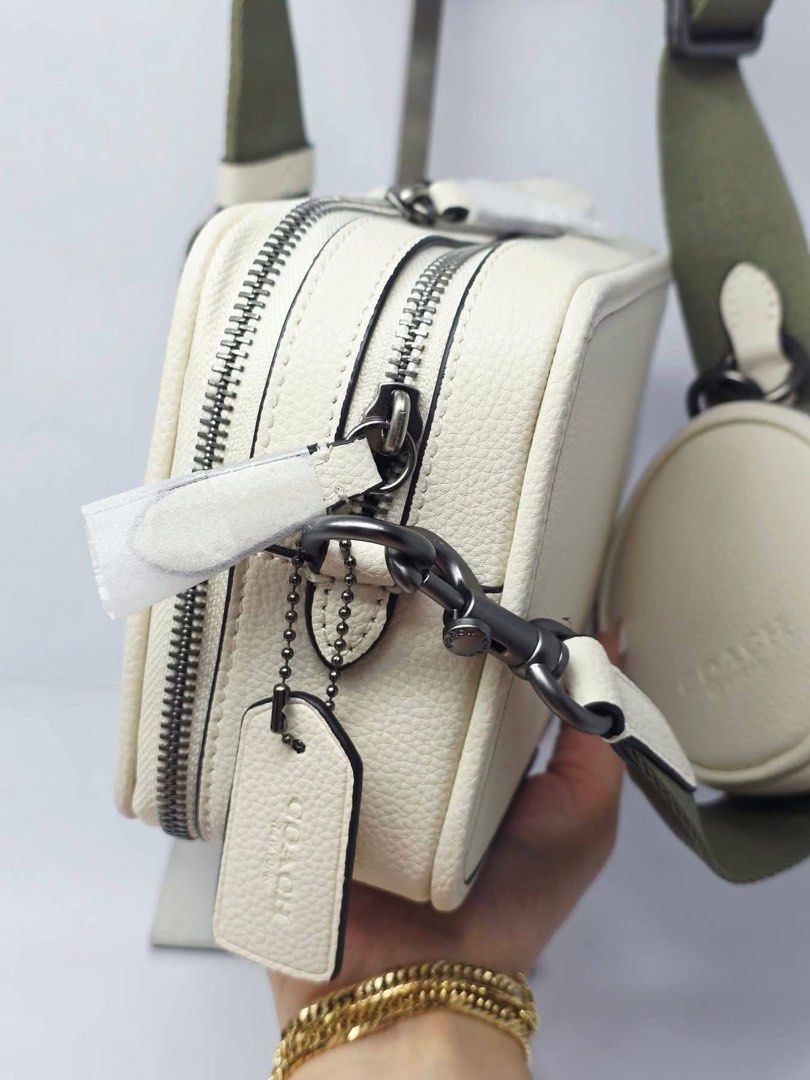 Coach Camera Bag With Round Coin Pouch Off White (Category: Cross-body Bags) located in Manila. Submitted by rachael_23 (Listing ID 1470622865, Image 2). Description: - Authentic Coach camera bag in off-white pebbled leather - Bold black Coach lettering on the front - Double zipped compartments with dark gunmetal hardware - Includes a matching round coin pouch attached to the strap - Adjustable olive green canvas shoulder strap with leather trim 