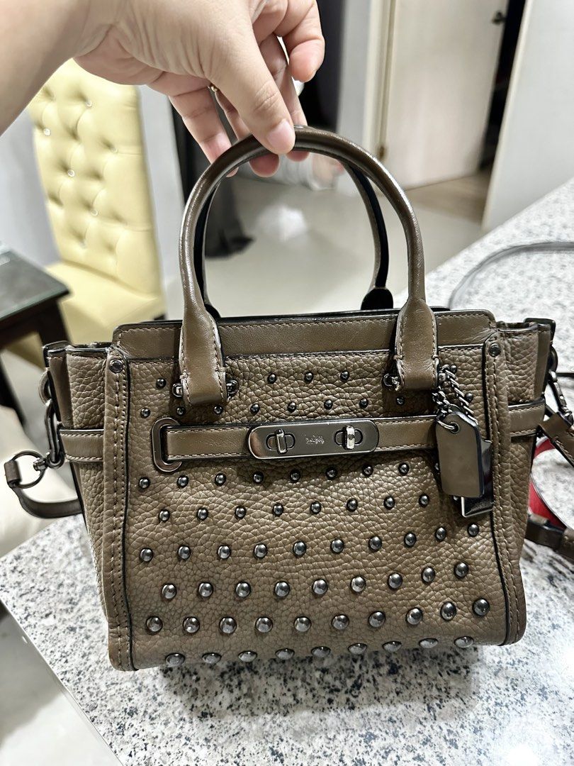 Coach Taupe Leather Studded Satchel Handbag (Category: Luxury Bags & Wallets) located in Cardona. Submitted by jaxdelossa10453 (Listing ID 1470612331, Image 1). Description: - Style: Taupe pebbled leather satchel with dark gunmetal hardware - Design: Fully covered metal-studded front with a secure turnlock closure - Carry options: Dual top handles + side rings ready for an optional crossbody strap - Extras: Includes matching leather hang tag - Ba