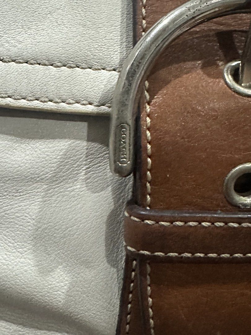 Coach White and Brown Leather Shoulder Bag (Category: Luxury Bags & Wallets) located in Manila. Submitted by zayzay08 (Listing ID 1470728047, Image 2). Description: Coach leather shoulder bag in white with brown trim and strap. Front flap pocket with buckle accent and silver-tone hardware. Top zipper closure with YKK zipper pull. Fabric lining inside with Coach creed patch and serial number stamp..