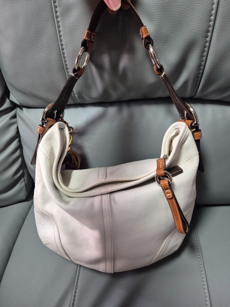 Coach White Leather Hobo Shoulder Bag with Cherry Charm (Category: Luxury Bags & Wallets) located in Mandaluyong City. Submitted by prelovedbydes19 (Listing ID 1470697659, Image 2). Description: - Authentic Coach white leather hobo bag - Features a contrasting brown adjustable handle - Secure top zip closure with polished silver-tone hardware - Roomy interior lined in signature Coach fabric with creed patch - Condition: Minor, normal wear on the 