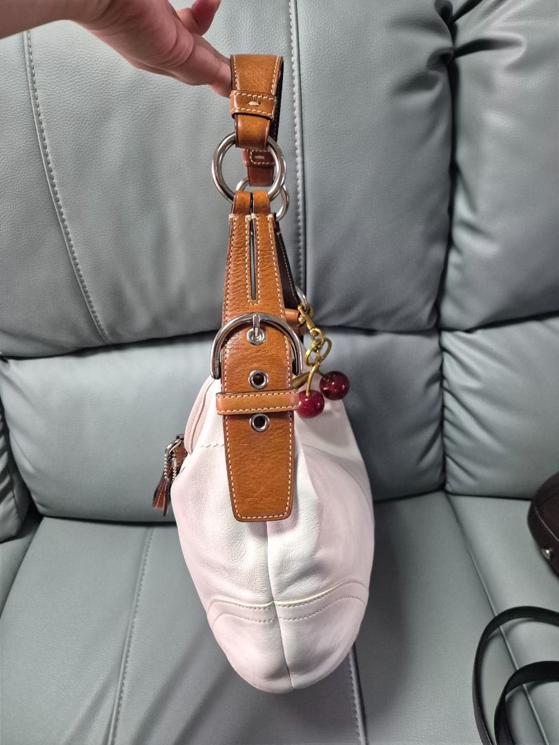 Coach White Leather Hobo Shoulder Bag with Cherry Charm (Category: Luxury Bags & Wallets) located in Mandaluyong City. Submitted by prelovedbydes19 (Listing ID 1470697659, Image 3). Description: - Authentic Coach white leather hobo bag - Features a contrasting brown adjustable handle - Secure top zip closure with polished silver-tone hardware - Roomy interior lined in signature Coach fabric with creed patch - Condition: Minor, normal wear on the 