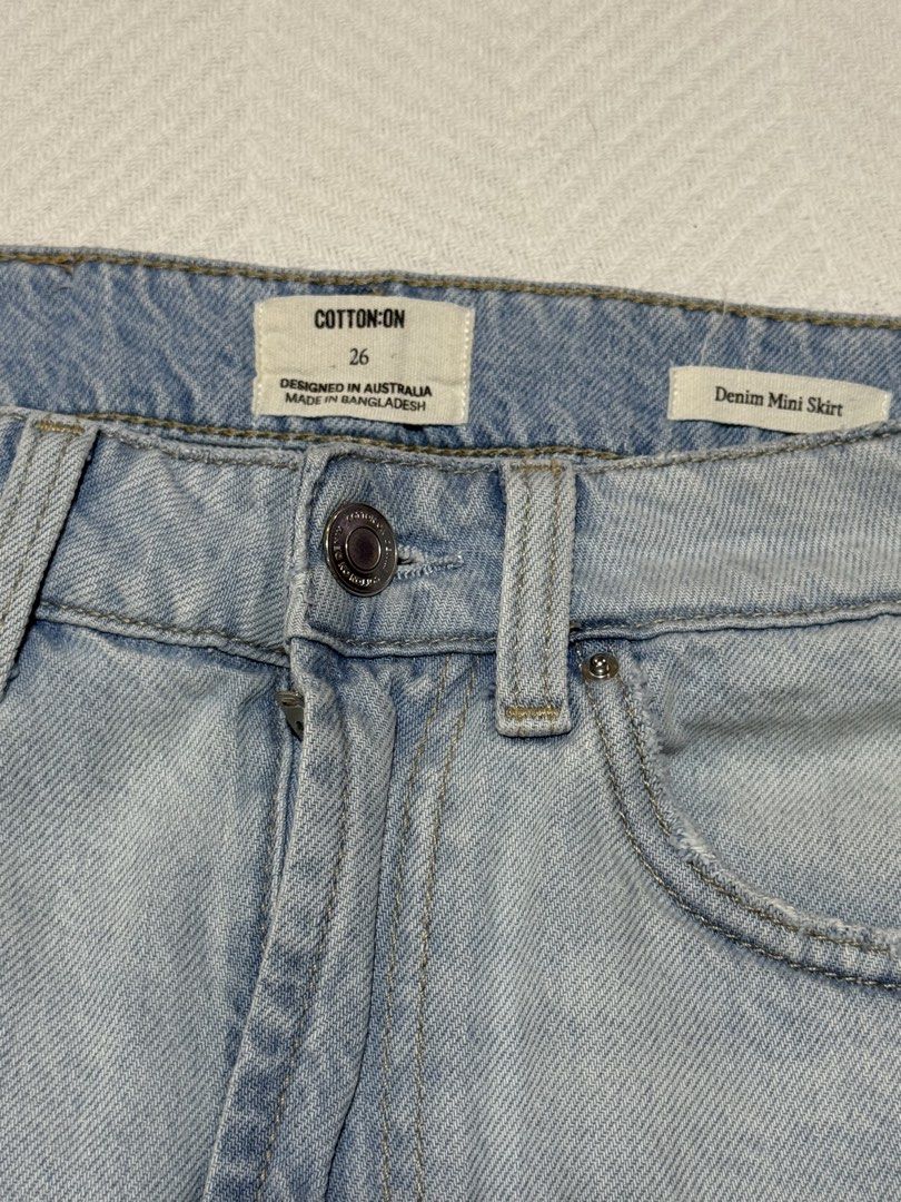 Cotton On Denim Mini Skirt Size 26 (Category: Skirts) located in Pateros City. Submitted by daisy03052000 (Listing ID 1470665992, Image 2). Description: - Brand: Cotton On - Size: 26 - Wash: Light wash denim - Style: Classic five-pocket mini skirt with button and zipper fly - Details: Leather patch on back waist and light distressing on back pockets - Condition: Excellent - Perfect for pairing with casual tees and sneakers bought in usa.