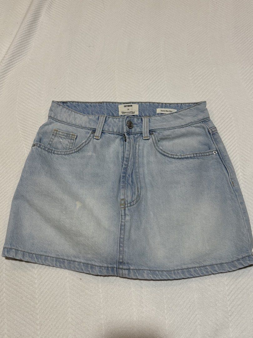Cotton On Denim Mini Skirt Size 26 (Category: Skirts) located in Pateros City. Submitted by daisy03052000 (Listing ID 1470665992, Image 1). Description: - Brand: Cotton On - Size: 26 - Wash: Light wash denim - Style: Classic five-pocket mini skirt with button and zipper fly - Details: Leather patch on back waist and light distressing on back pockets - Condition: Excellent - Perfect for pairing with casual tees and sneakers bought in usa.