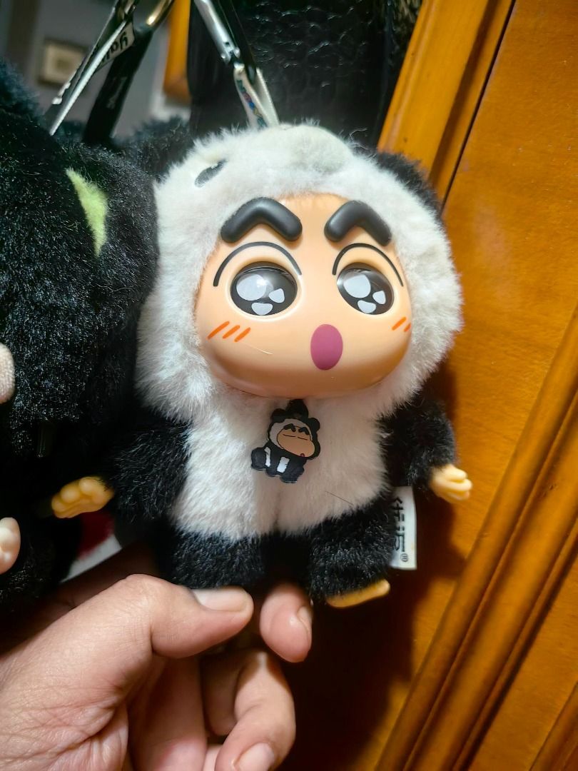 Crayon Shin-chan Panda Plush Keychain Bag Charm (Category: Plushies & Soft Toys) located in Davao. Submitted by thefrugalshop (Listing ID 1470627229, Image 1). Description: - Character: Crayon Shin-chan in a fluffy panda suit - Features: Glossy plastic face, open-mouth expression, and a dangling mini panda charm - Design: Black and white fur body with bright yellow hands and feet - Versatile Use: Comes with a sturdy clip for bags, backpacks, or k