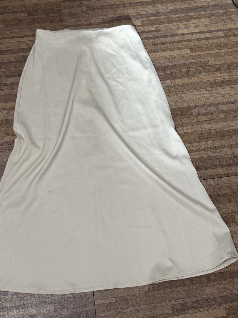 Cream Satin Maxi Skirt (Category: Skirts) located in Manila. Submitted by razielaninon.bird (Listing ID 1470604147, Image 2). Description: - Color: Cream - Material: Soft satin fabric with a smooth texture and fluid drape - Cut: High-waisted with a slight flare at the hem - Style: Minimalist and versatile, easy to dress up or down - Length: Midi.