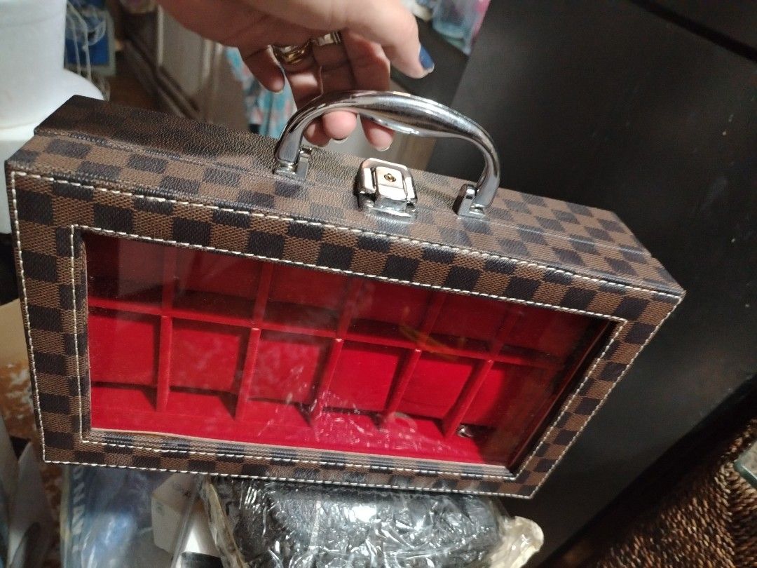 Damier Ebene Watch Box Storage Case with Handle (Category: Accessory Holder, Box & Organizers) located in Quezon City. Submitted by shewool (Listing ID 1470590284, Image 2). Description: - Brown checkerboard pattern exterior - Holds 10 watches on individual plush red velvet pillows - Clear display window on the top lid for easy viewing - Sturdy silver metal handle and secure clasp closure - Hard structured case keeps your collection organized and