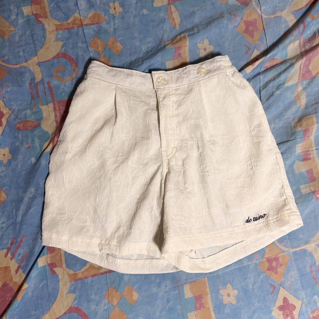 De Tsino Cream Shorts (Category: Shorts) located in Mandaluyong City. Submitted by johnsgaragesale (Listing ID 1470641131, Image 3). Description: - Brand: De Tsino - Color: Clean cream / white - Features: Gartered waist with button closure, functional pockets, and embroidered logo near the hem - Fabric: Textured pattern, comfortable for warm days - Measurements: Waist 28 to 34 inches, Length 15.5 inches, Hips 44 inches - SRP: 1750.