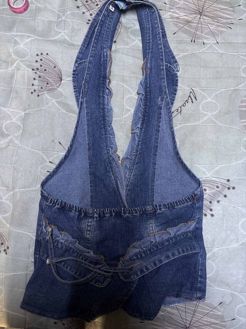 Denim halter top vest with ruffle trim (Category: Sleeveless) located in Caloocan City. Submitted by boldcrystal.64c51d (Listing ID 1470565480, Image 2). Description: - Style: Dark wash denim halter top - Neckline: Deep V-neck with frayed ruffle trim - Closure: Front button with two decorative buttons - Back Details: Elastic band at the waist and overlapping denim pocket-like details at the hem - Material: Comfortable blue denim - Condition: Bran