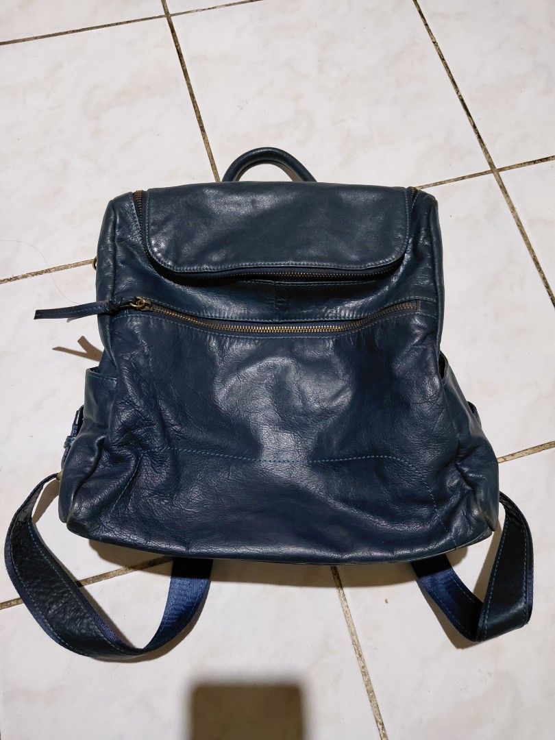 Design by Kang Jung Hee blue leather backpack (Category: Backpacks) located in Bacolod City. Submitted by cano47 (Listing ID 1470684837, Image 1). Description: - Brand/Designer: Design by Kang Jung Hee - Color: Dark blue - Material: Soft wrinkled leather with brass hardware and adjustable blue fabric straps - Compartments: Front exterior zip pocket, main zip compartment, and top grab handle - Interior: Beige fabric lining with an extra zip pocket