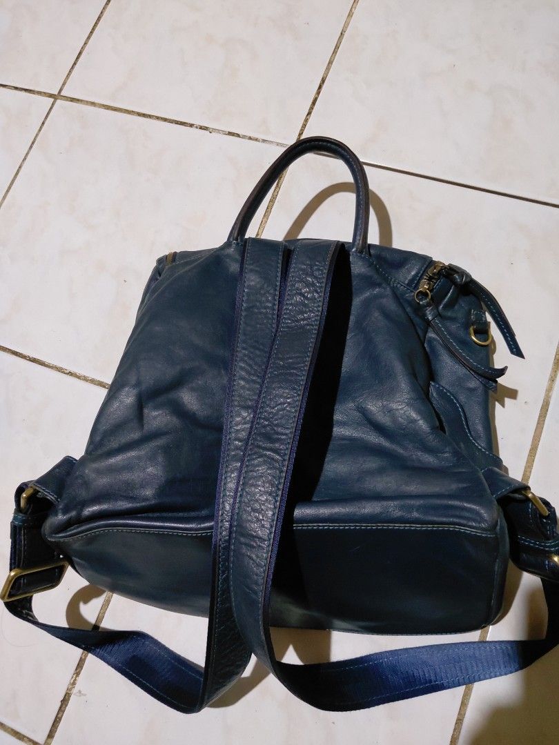 Design by Kang Jung Hee blue leather backpack (Category: Backpacks) located in Bacolod City. Submitted by cano47 (Listing ID 1470684837, Image 2). Description: - Brand/Designer: Design by Kang Jung Hee - Color: Dark blue - Material: Soft wrinkled leather with brass hardware and adjustable blue fabric straps - Compartments: Front exterior zip pocket, main zip compartment, and top grab handle - Interior: Beige fabric lining with an extra zip pocket