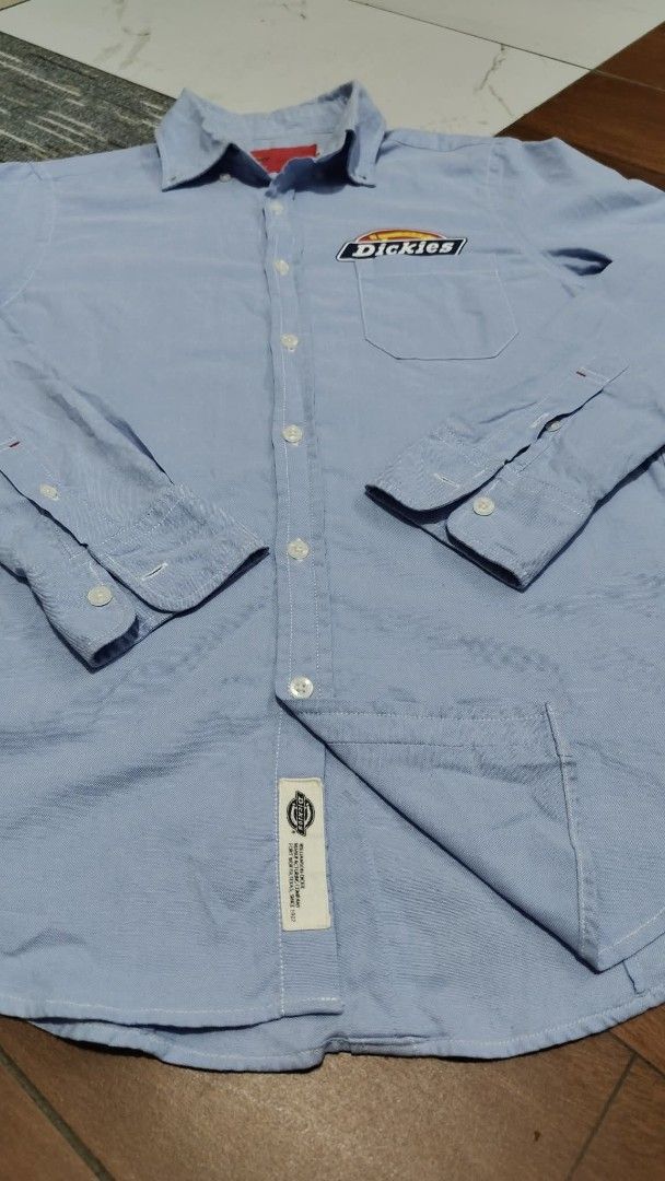 Dickies Light Blue Long Sleeve Button-Down Shirt (Category: Tshirts & Polo Shirts ) located in Bulacan. Submitted by adrian2325 (Listing ID 1470641846, Image 3). Description: - Brand: Dickies - Color: Light Blue - Style: Long-sleeve button-down shirt with classic collar - Material: 65% Cotton, 35% Polyester blend for comfort and durability - Details: Left chest pocket with iconic Dickies logo patch - Cuffs: Button cuffs on sleeves - Hem: Branded 