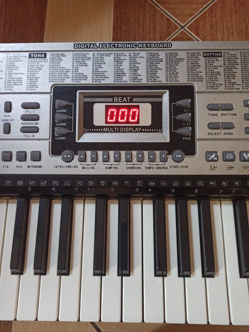 Digital Electronic Keyboard with Power Adapter (Category: Other Home Appliances) located in Manila. Submitted by crafters0001 (Listing ID 1470639480, Image 1). Description: - Type: 54-key digital electronic keyboard (standard layout) - Color: Sleek silver and black control panel - Display: Digital screen showing clear beat numbers - Features: Built-in speakers, various tone and rhythm settings, and a number pad for direct selection - Inclusion: M