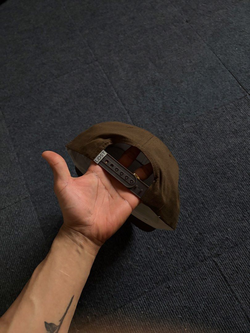 Drake Waterfowl Brown Snapback Cap (Category: Caps & Hats) located in Manila. Submitted by toys_hats005 (Listing ID 1470629528, Image 2). Description: - Brand/Style: Drake Waterfowl snapback hat in brown - Design: Structured crown, flat brim, and stylish contrast rope detail across the front - Details: Front patch logo and Lost brand tab at the back snap - Comfort: Clean inside lining with custom branded taping - Condition/Fit: Adjustable snap cl