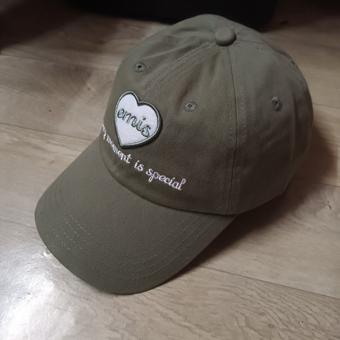 Emis Heart Logo Cap (Category: Caps & Hats) located in Manila. Submitted by itsnik444 (Listing ID 1470639818, Image 2). Description: - Brand: Emis - Color: Olive green - Design: Embroidered heart patch with 'emis' text and 'every moment is special' lettering - Material: 100% cotton - Closure: Adjustable strapback with branded metal buckle - Details: Branded interior taping and tag - Condition: Clean and ready to wear.