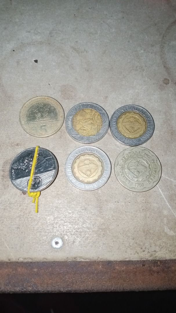 Error and commemorative coins., presyohan nyo na lang (Category: Currency) located in Caloocan City. Submitted by aaliyahsison09 (Listing ID 1470663374, Image 2). Description: - Philippine currency coin collection - Includes commemorative and standard designs - Features 10-peso bimetallic and 5-peso coins - Visible dates include 1998, 2003, and others - Shows natural discoloration and surface wear - Sold as a bundle lot secured with a rubber band