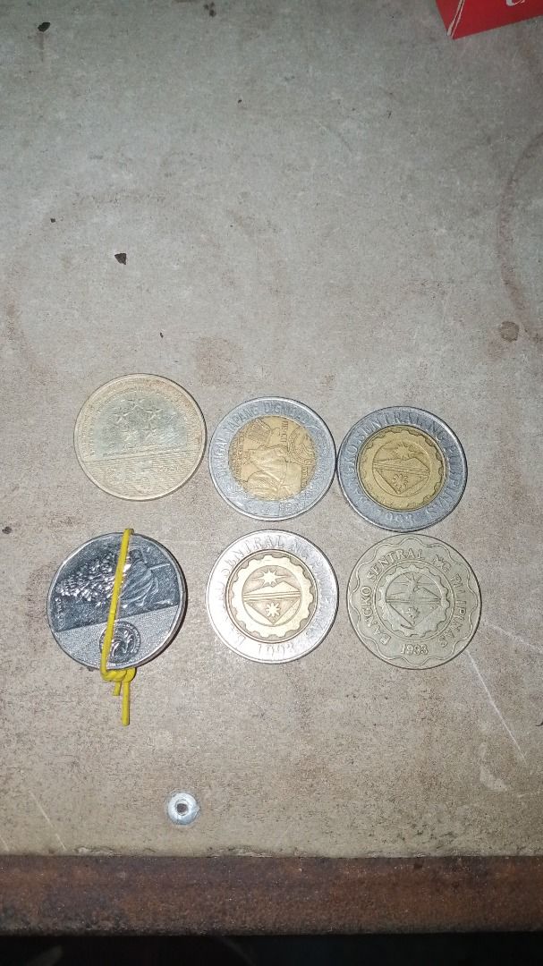 Error and commemorative coins., presyohan nyo na lang (Category: Currency) located in Caloocan City. Submitted by aaliyahsison09 (Listing ID 1470663374, Image 1). Description: - Philippine currency coin collection - Includes commemorative and standard designs - Features 10-peso bimetallic and 5-peso coins - Visible dates include 1998, 2003, and others - Shows natural discoloration and surface wear - Sold as a bundle lot secured with a rubber band