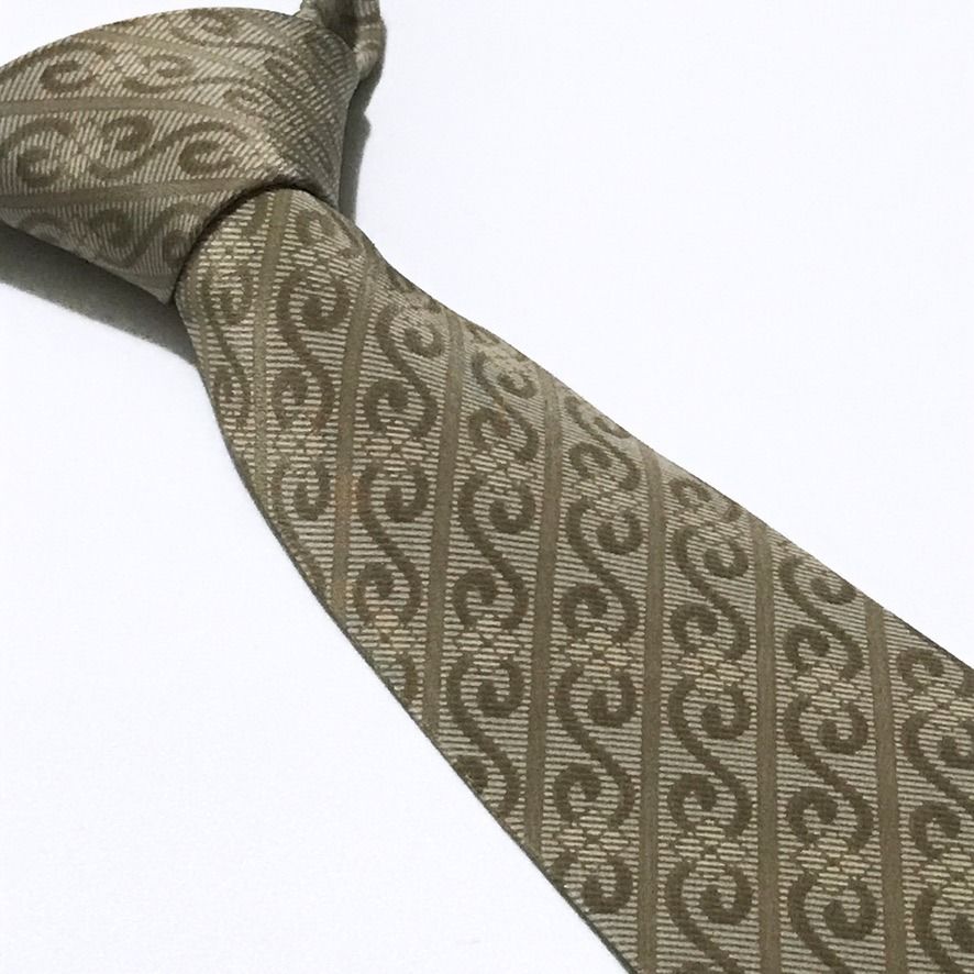Excellent Geometric Stripes Pattern Beige Neck Tie (Category: Ties) located in Taguig. Submitted by retrogaze (Listing ID 1470706514, Image 1). Description: This 100% silk necktie by Excellent features a warm beige-champagne ground. The blade is decorated with a repeating geometric bias stripe pattern showcasing interlocking 'S'-scroll motifs and wavy ribbon tendrils in a taupe-brown shade. Recommended Suit & Shirt Pairings: • The Executive Class