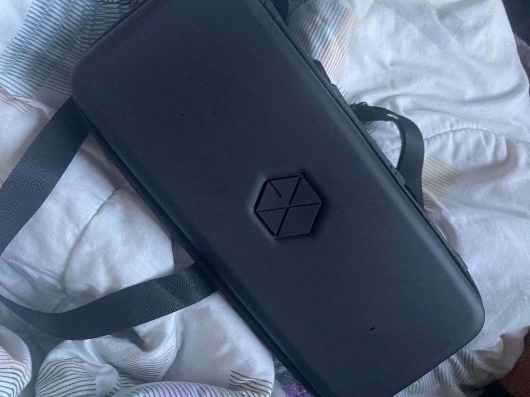 EXO Lightstick Pouch (Category: Cases & Sleeves) located in San Pablo. Submitted by vrmthrsainz (Listing ID 1470665848, Image 1). Description: - Official EXO black hard shell carrying case - Features a sleek EXO logo badge on the front - Secure zip closure with an adjustable shoulder strap included - Organized interior with molded compartments, elastic straps, and mesh zippered pockets - Exterior shows minor surface scuffs from normal handling - 