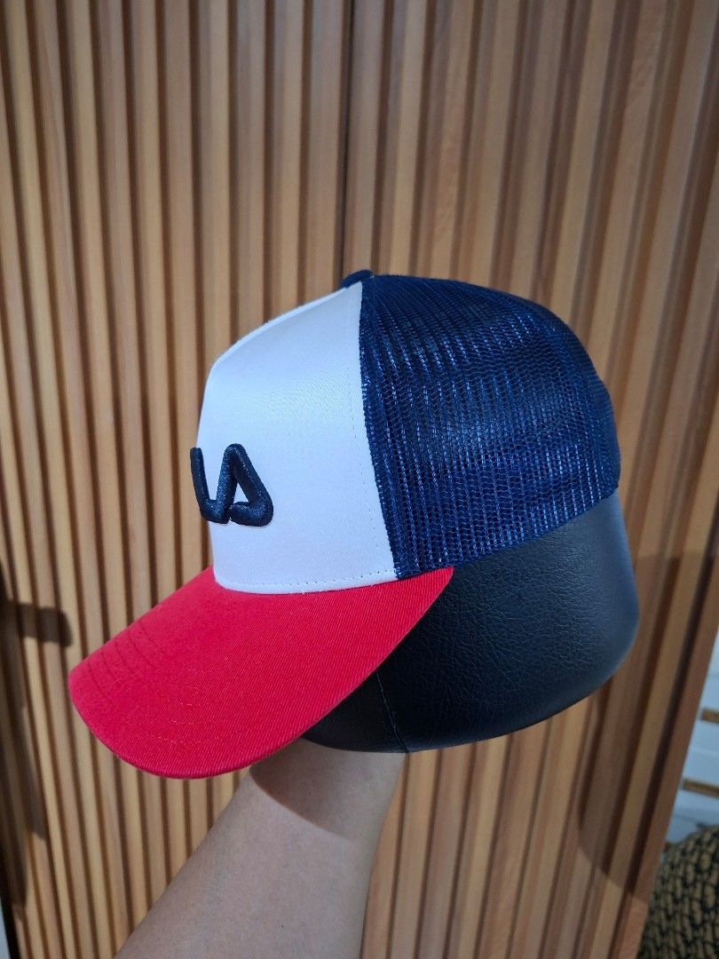 Fila Trucker Cap Red White Blue (Category: Caps & Hats) located in Cebu City. Submitted by anton_delos_reyes (Listing ID 1470705694, Image 2). Description: - Brand: Fila - Colorway: Red, white, and navy blue - Design: Foam front panel with raised embroidered Fila logo and curved red brim - Comfort: Breathable mesh back panels - Fit: Adjustable snapback closure for a custom fit - Condition: Clean inside and out, well-maintained.
