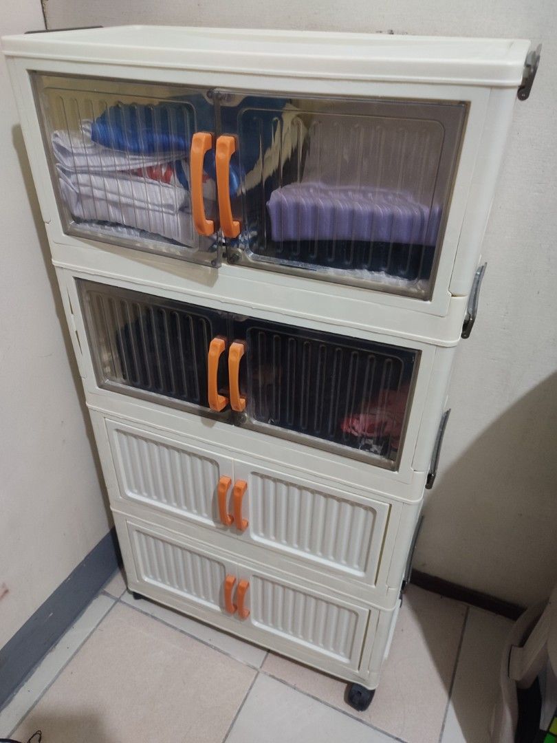 Foldable Storage Cabinet w/ wheels (Category: Shelves, Cabinets & Racks) located in Paranaque City. Submitted by breealigam24841 (Listing ID 1470651414, Image 2). Description: - Brand: HALOO 4-tier foldable storage cabinet - Dimensions: 50 x 24 x 92 cm - Design: Cream white body, clear doors, and vibrant orange handles - Mobility: Equipped with universal wheels at the bottom for easy movement - Assembly: Quick folding structure for hassle-free se