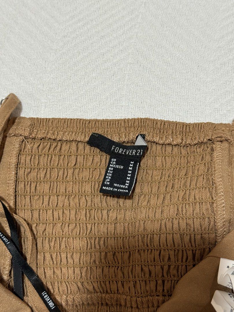 Forever 21 Brown Halter Crop Top Size M (Category: Sleeveless) located in Pateros City. Submitted by daisy03052000 (Listing ID 1470695979, Image 3). Description: - Brand: Forever 21 - Size: Medium - Color: Brown - Condition: Brand new with tags (BNWT), unworn - Features: Halter neck, triangular front hem, adjustable thin straps, elastic smocked back panel for a comfortable fit.