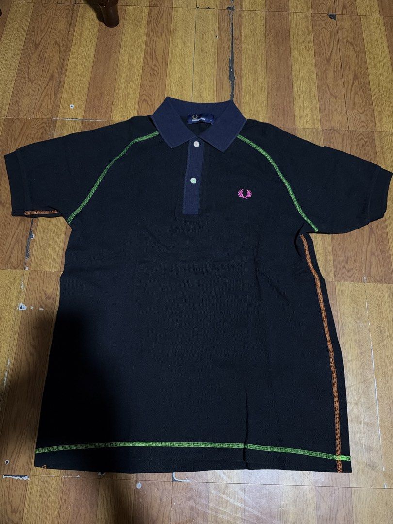 Fred Perry Black Polo Shirt with Contrast Stitching (Category: Tshirts & Polo Shirts ) located in Manila. Submitted by annabananna (Listing ID 1470685577, Image 1). Description: - Brand: Fred Perry - Color: Black with dark blue collar/placket and green/orange zigzag stitching - Details: Iconic pink embroidered laurel wreath logo on chest - Fit: Classic fit, short sleeves, two-button placket - Material: Lightweight, comfortable cotton - Condition: