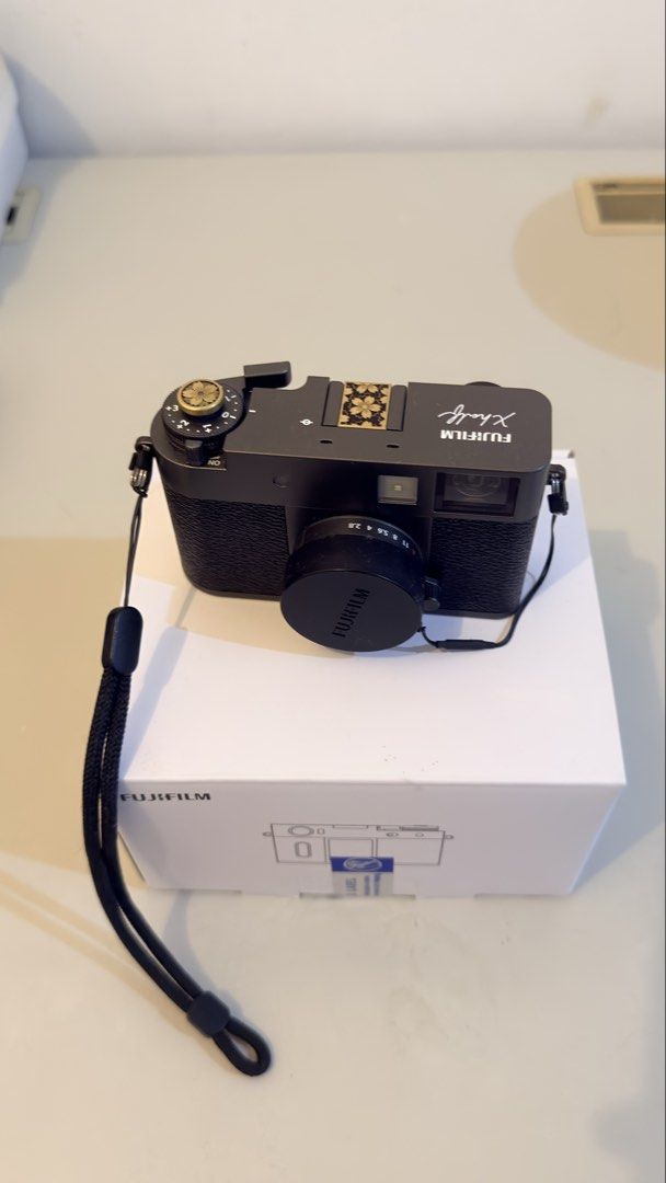 Fujifilm Xhalf Digital Camera with Box and Strap (Category: Cameras) located in Santa Maria. Submitted by jestonicruz (Listing ID 1470661872, Image 1). Description: - Model: Fujifilm Xhalf Digital Camera (Black) - Condition: Clean exterior finish, excellent ready-to-use condition - Inclusions: Original white box, lens cap, and attached black neck strap - Customizations: Decorative floral cover on the hot shoe mount and matching floral shutter but