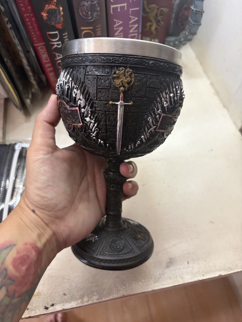 Game of Thrones Chalice Goblet Cup (Category: Coffee & Tea Tableware) located in Marikina City. Submitted by phelinky_finds (Listing ID 1470595197, Image 3). Description: - Game of Thrones themed goblet - Heavy resin exterior with intricate sword motifs and House sigils - Iron Throne wrap design - Safe stainless steel inner lining - Wide, sturdy base for stability - Ideal as a display piece or unique drinking vessel for fans.