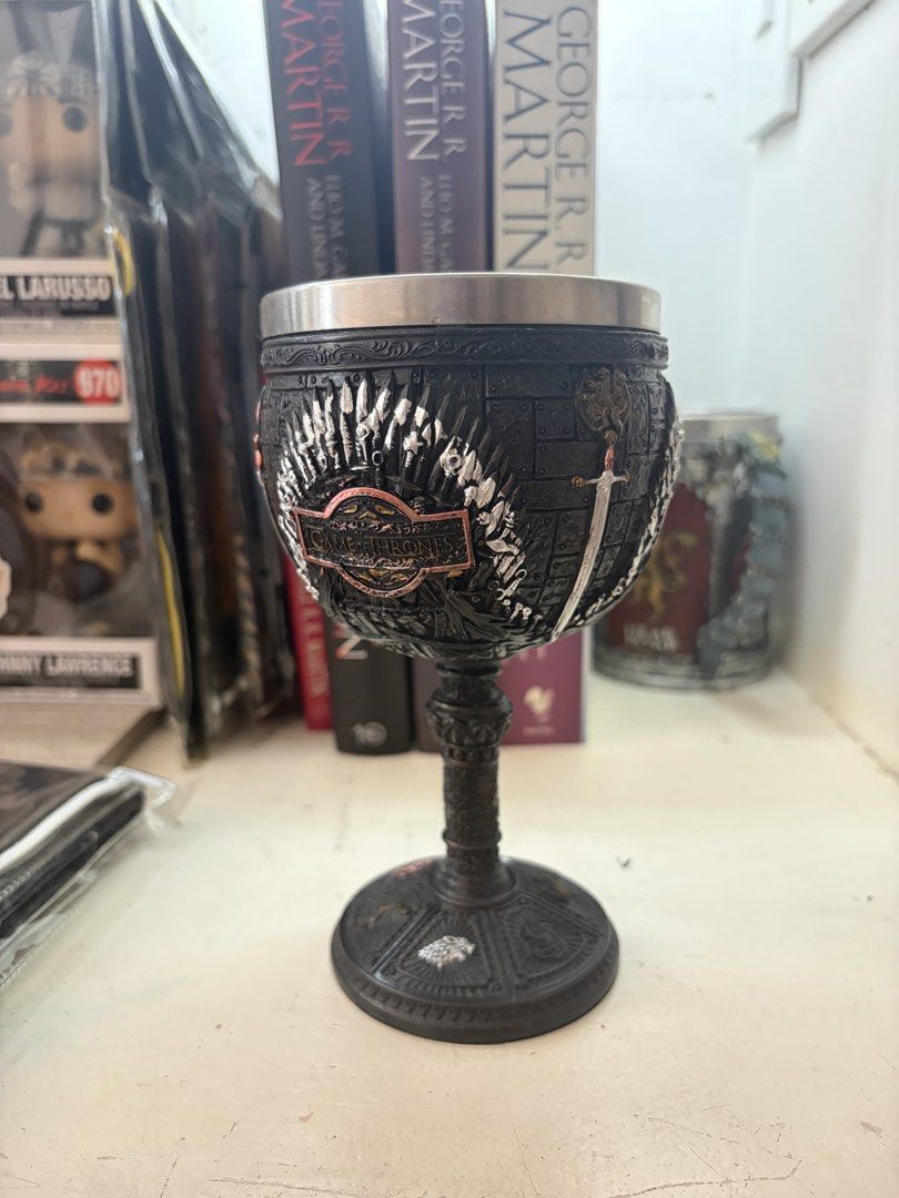 Game of Thrones Chalice Goblet Cup (Category: Coffee & Tea Tableware) located in Marikina City. Submitted by phelinky_finds (Listing ID 1470595197, Image 1). Description: - Game of Thrones themed goblet - Heavy resin exterior with intricate sword motifs and House sigils - Iron Throne wrap design - Safe stainless steel inner lining - Wide, sturdy base for stability - Ideal as a display piece or unique drinking vessel for fans.