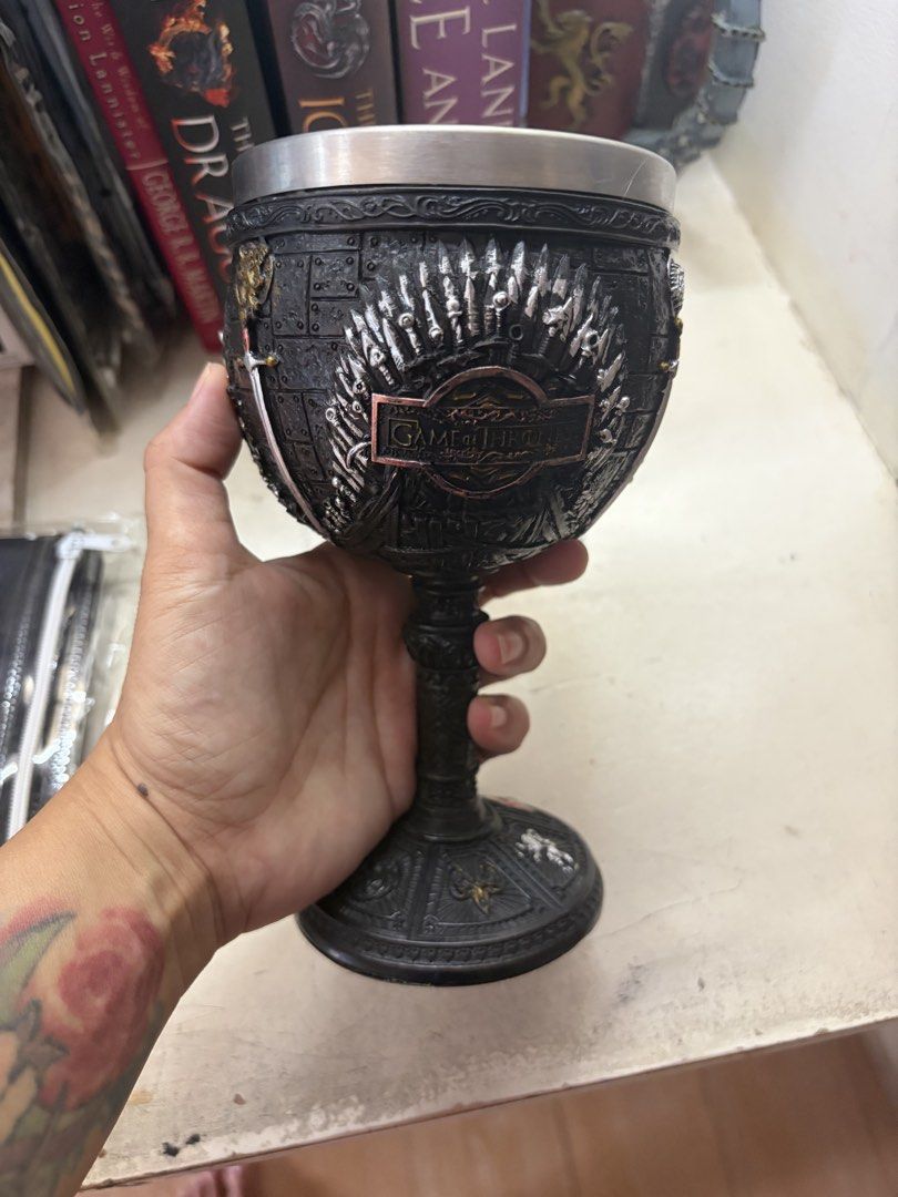 Game of Thrones Chalice Goblet Cup (Category: Coffee & Tea Tableware) located in Marikina City. Submitted by phelinky_finds (Listing ID 1470595197, Image 2). Description: - Game of Thrones themed goblet - Heavy resin exterior with intricate sword motifs and House sigils - Iron Throne wrap design - Safe stainless steel inner lining - Wide, sturdy base for stability - Ideal as a display piece or unique drinking vessel for fans.