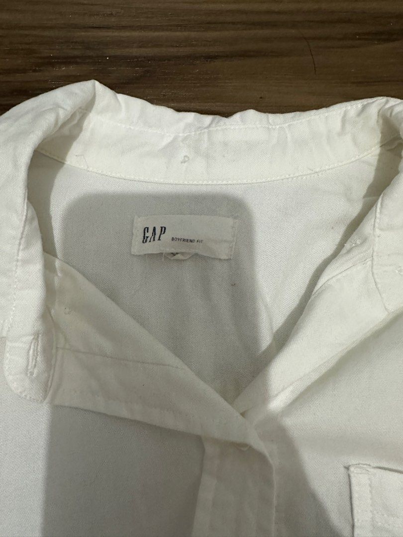 Gap White Boyfriend Fit Button Down Shirt Size S (Category: Shirts) located in Paranaque City. Submitted by declutterwyae (Listing ID 1470645674, Image 3). Description: - Brand: Gap - Color: Clean White - Size: Small - Style: Relaxed boyfriend fit - Details: Long sleeves with button cuffs, front chest pocket, curved hem, and classic collar - Condition: Excellent / Clean - Versatility: Perfect for casual or smart-casual outfits.
