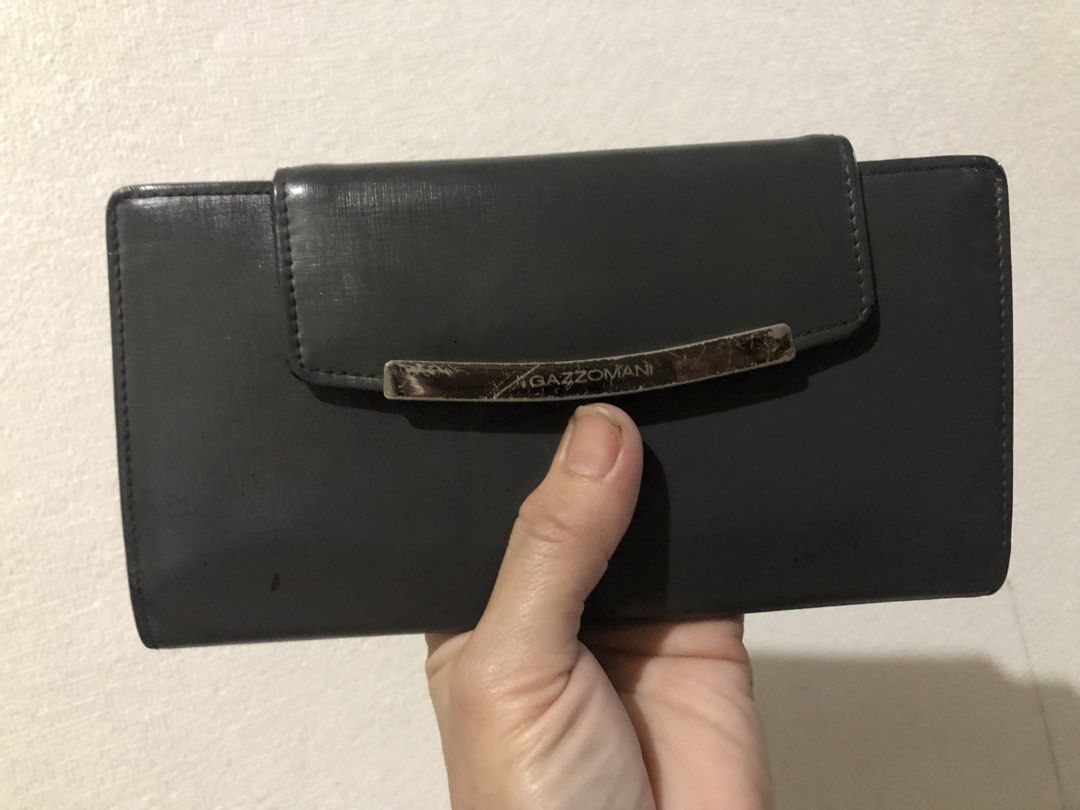 Gazzomani Dark Grey Long Wallet (Category: Wallets & Card holders) located in Valenzuela. Submitted by nixs2722 (Listing ID 1470705267, Image 1). Description: - Brand/Model: Gazzomani long wallet in dark grey - Finish: Textured with snap closure - Exterior: Metal hardware plate on front with visible scratches and wear; back zip pocket with a custom zip pull - Interior: Multiple card slots and an ID window - Condition: Used with noticeable signs o