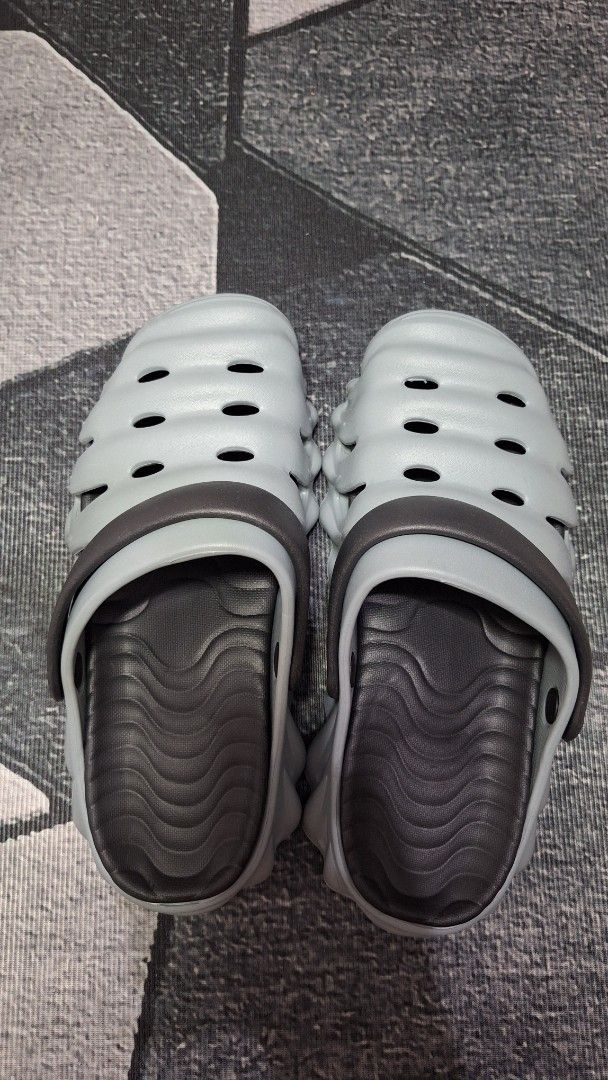 Grey Clogs Sandals Size 44-45 (Category: Slippers & Slides) located in Mandaluyong City. Submitted by erick1213_ (Listing ID 1470682110, Image 3). Description: - Color: Grey with dark grey straps - Size: 44-45 - Features: Unique wavy ribbed exterior, side ventilation cutouts, and wavy textured insoles - Sole: Textured anti-slip sole for better grip - Comfort: Super comfortable, lightweight, and easy to wash - Origin: Made in China.