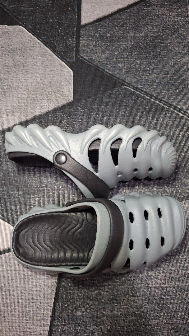 Grey Clogs Sandals Size 44-45 (Category: Slippers & Slides) located in Mandaluyong City. Submitted by erick1213_ (Listing ID 1470682110, Image 1). Description: - Color: Grey with dark grey straps - Size: 44-45 - Features: Unique wavy ribbed exterior, side ventilation cutouts, and wavy textured insoles - Sole: Textured anti-slip sole for better grip - Comfort: Super comfortable, lightweight, and easy to wash - Origin: Made in China.