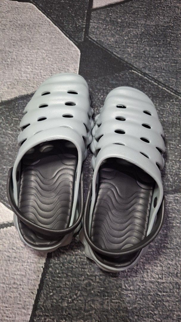 Grey Clogs Sandals Size 44-45 (Category: Slippers & Slides) located in Mandaluyong City. Submitted by erick1213_ (Listing ID 1470682110, Image 2). Description: - Color: Grey with dark grey straps - Size: 44-45 - Features: Unique wavy ribbed exterior, side ventilation cutouts, and wavy textured insoles - Sole: Textured anti-slip sole for better grip - Comfort: Super comfortable, lightweight, and easy to wash - Origin: Made in China.